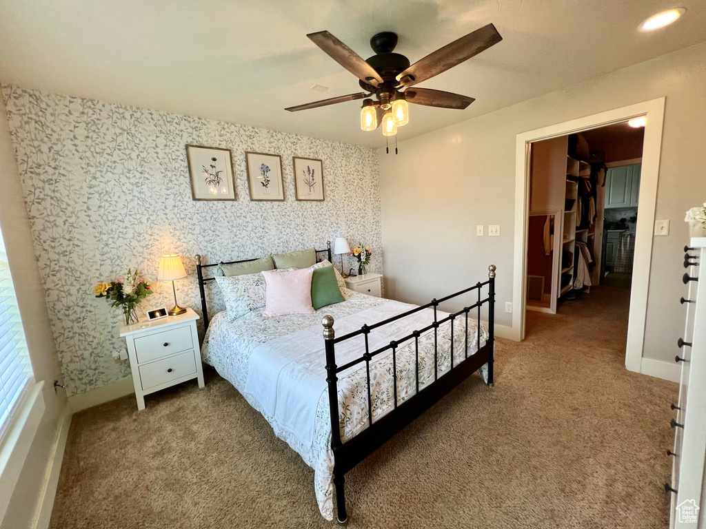 Carpeted bedroom with a spacious closet and ceiling fan