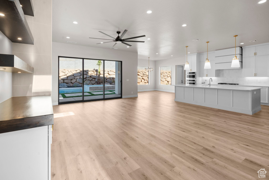 Unfurnished living room with sink, light hardwood / wood-style flooring, and ceiling fan