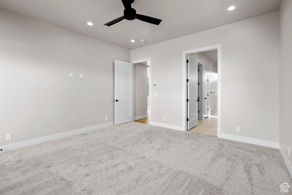 Unfurnished bedroom with ceiling fan and light colored carpet