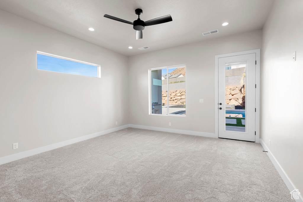 Carpeted empty room featuring ceiling fan