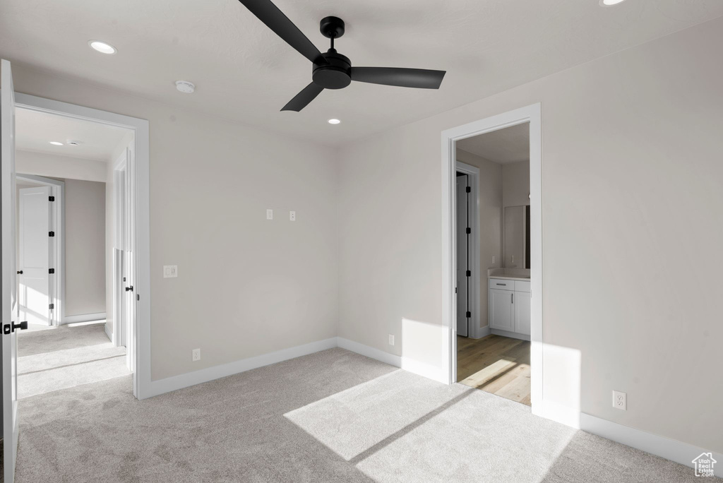 Unfurnished bedroom with connected bathroom, ceiling fan, and light colored carpet