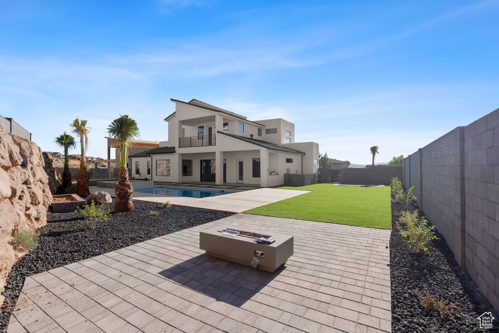 Rear view of house featuring a patio, a balcony, a yard, a fenced in pool, and a fire pit