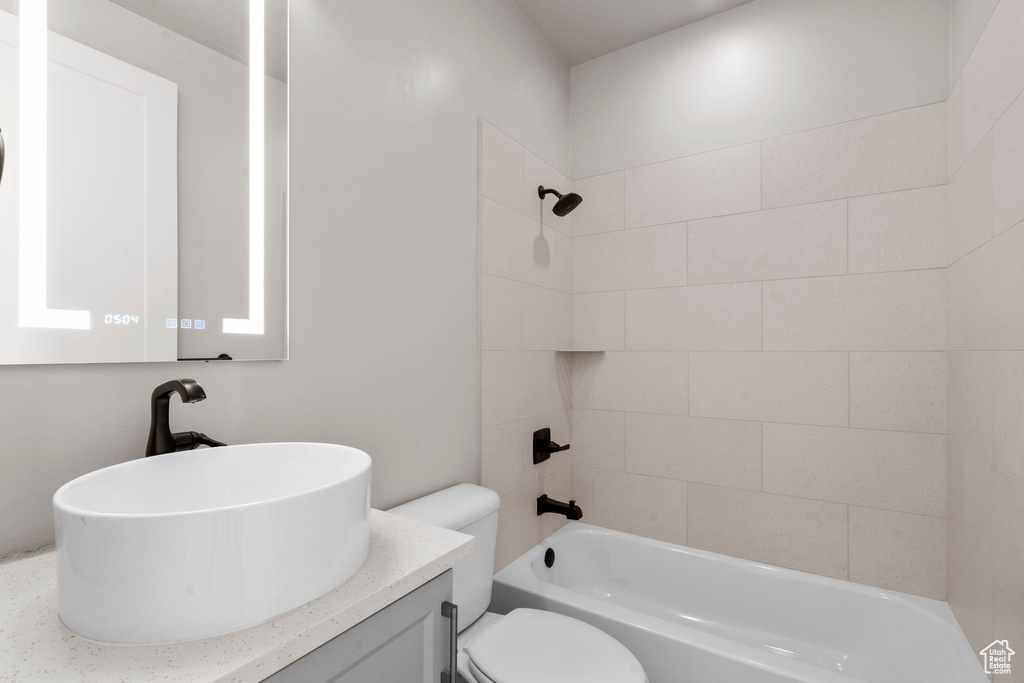 Full bathroom featuring tiled shower / bath combo, vanity, and toilet