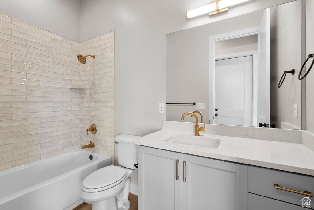 Full bathroom with tiled shower / bath combo, vanity, and toilet