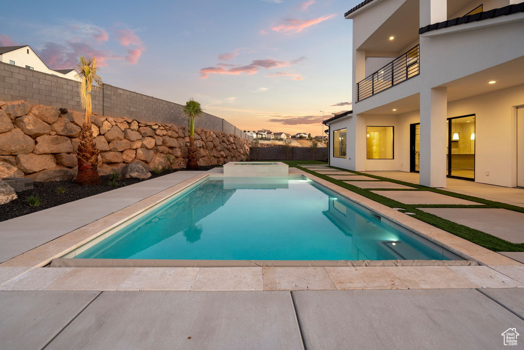 Pool at dusk featuring a patio area