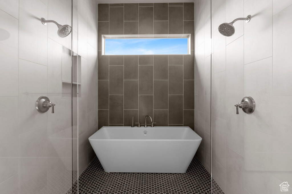 Bathroom featuring tile walls, tile patterned flooring, and plus walk in shower