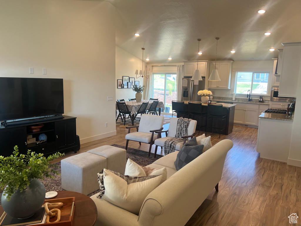 Living room featuring hardwood / wood-style flooring, lofted ceiling, sink, and plenty of natural light