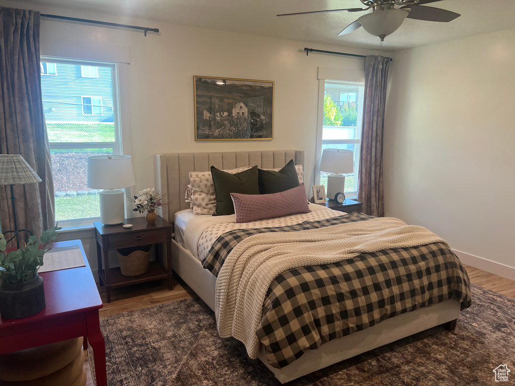 Bedroom with multiple windows, hardwood / wood-style floors, and ceiling fan