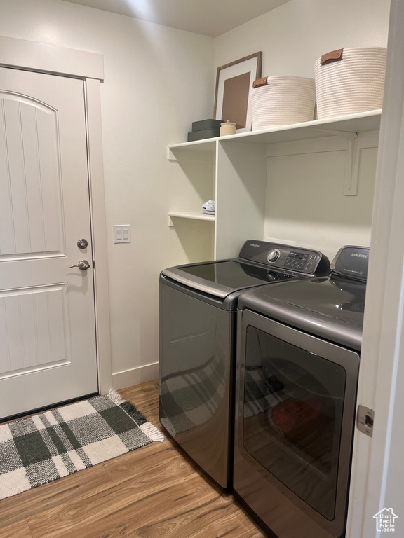 Laundry area with washer and clothes dryer and hardwood / wood-style floors