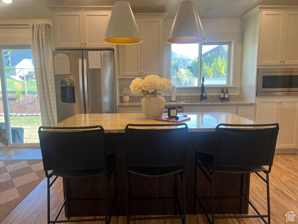 Kitchen with a kitchen island, white cabinets, light wood-type flooring, and stainless steel appliances