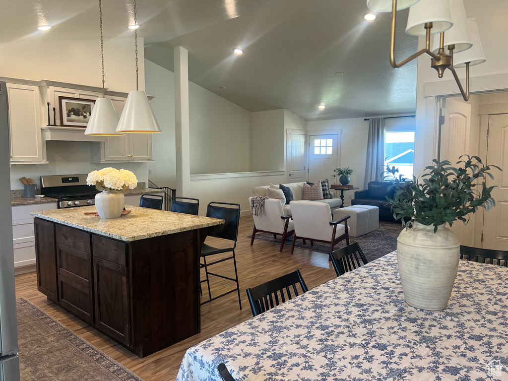 Kitchen featuring dark hardwood / wood-style flooring, white cabinets, stainless steel stove, a center island, and lofted ceiling