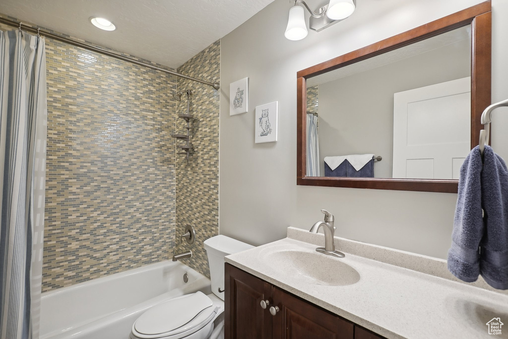 Full bathroom featuring vanity, shower / bathtub combination with curtain, and toilet