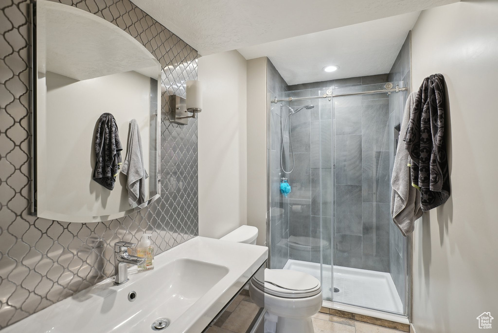 Bathroom featuring tile patterned flooring, a shower with shower door, toilet, and sink