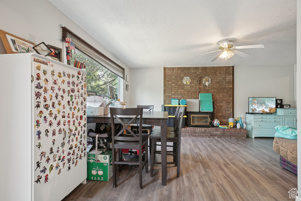 Dining space with brick wall, a textured ceiling, ceiling fan, and wood-type flooring