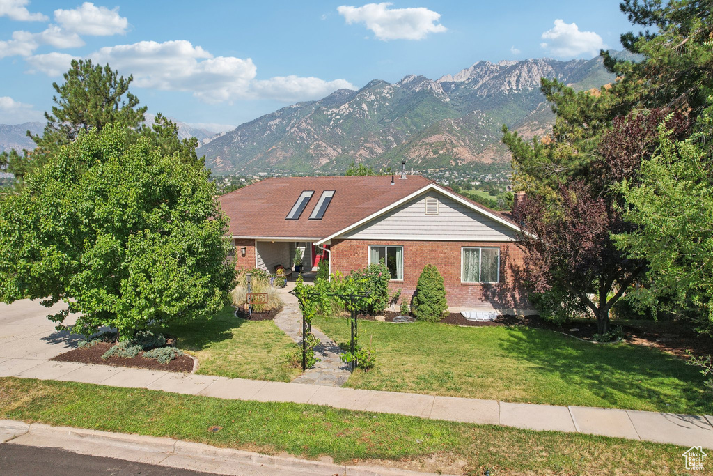 Ranch-style home featuring a mountain view and a front yard