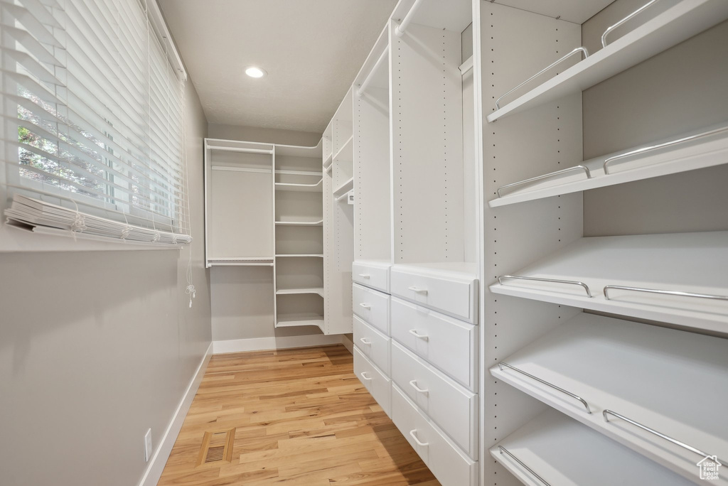 Spacious closet with light hardwood / wood-style flooring