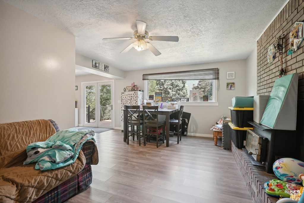 Dining space with light wood-type flooring, ceiling fan, french doors, and a textured ceiling