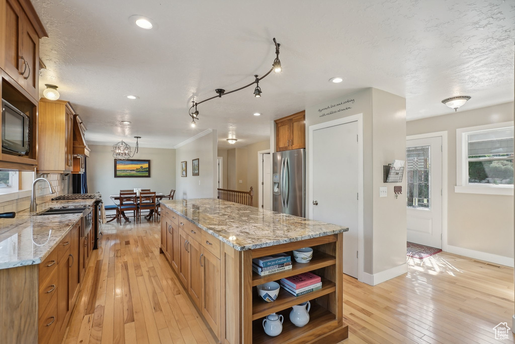 Kitchen with light stone counters, light hardwood / wood-style floors, a kitchen island, rail lighting, and stainless steel refrigerator with ice dispenser