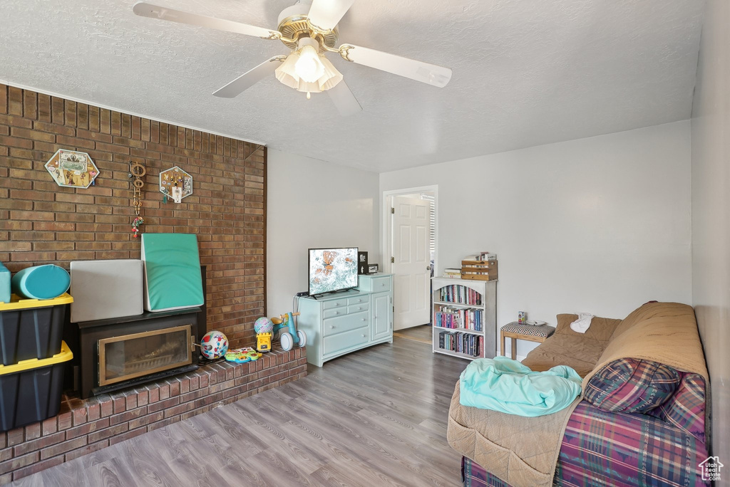 Living room with brick wall, a textured ceiling, ceiling fan, and hardwood / wood-style floors