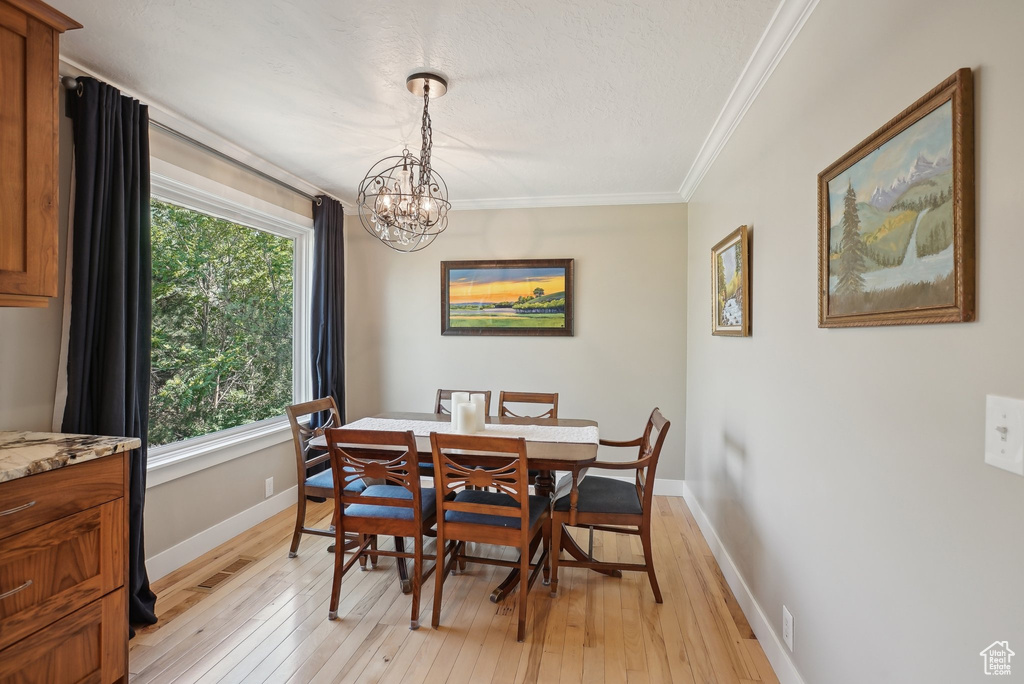 Dining space featuring crown molding, light wood-type flooring, and an inviting chandelier