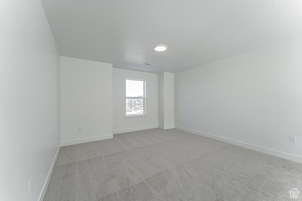 Unfurnished room featuring a textured ceiling and light colored carpet