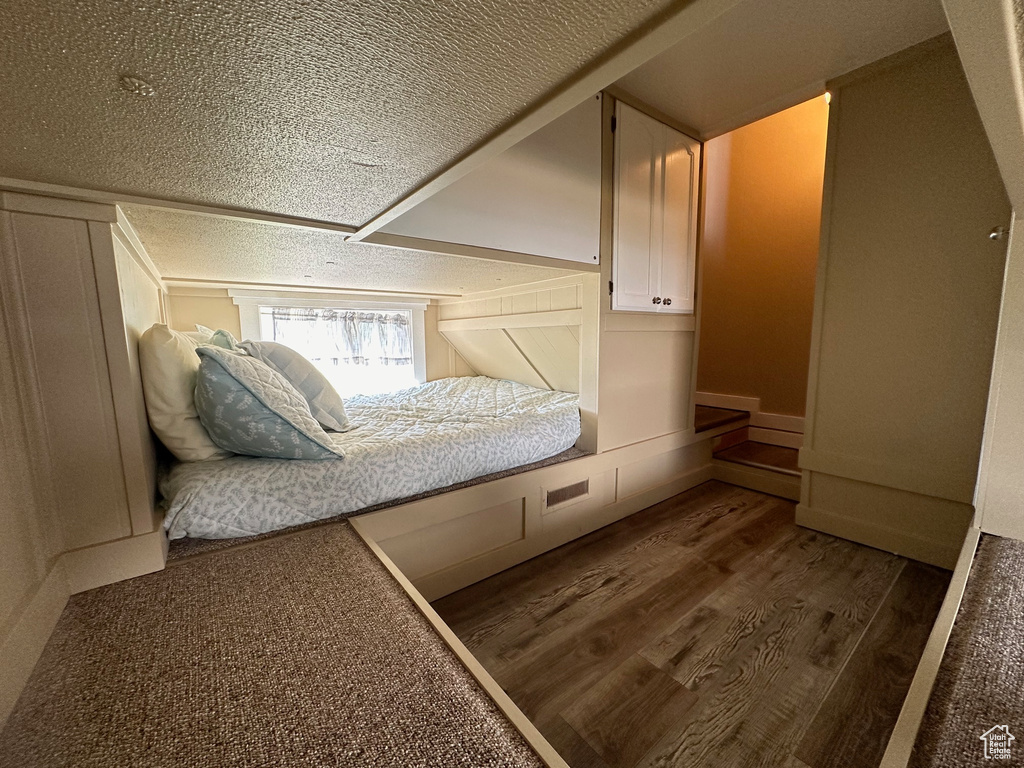 Unfurnished bedroom with a textured ceiling and wood-type flooring