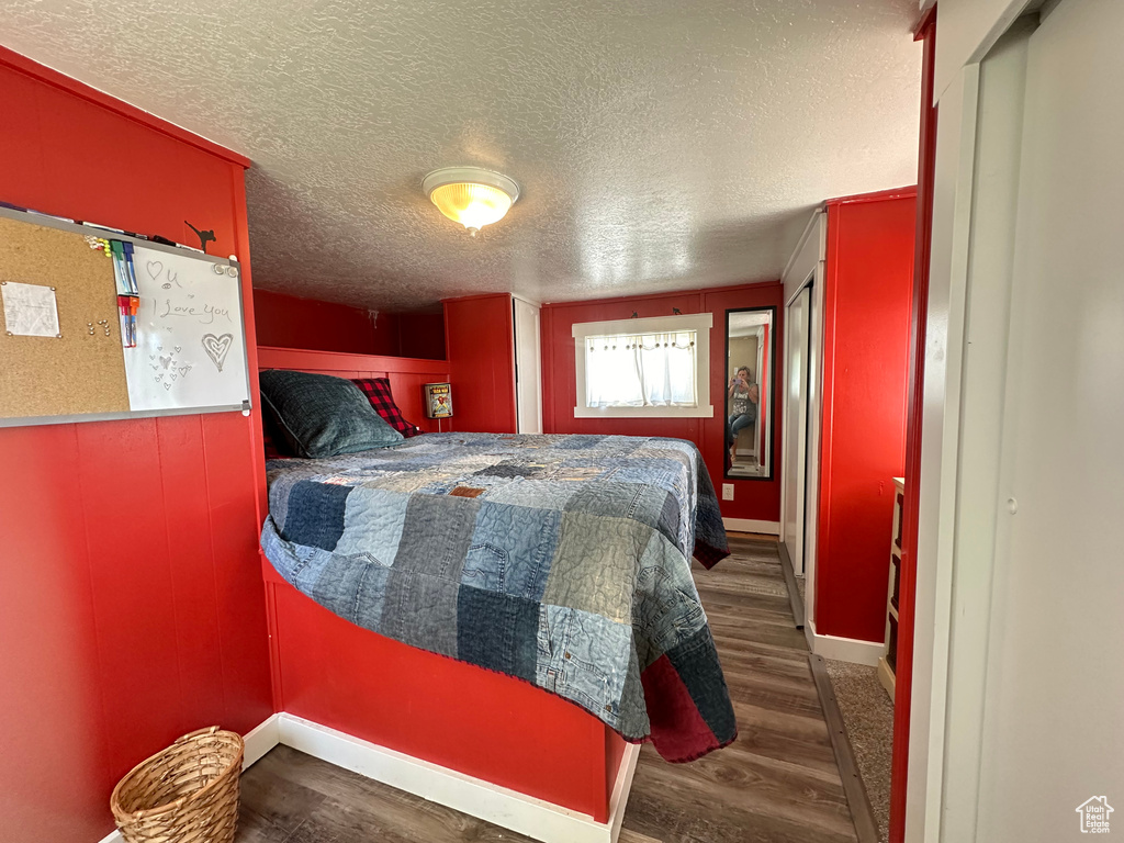 Bedroom with a textured ceiling and dark wood-type flooring