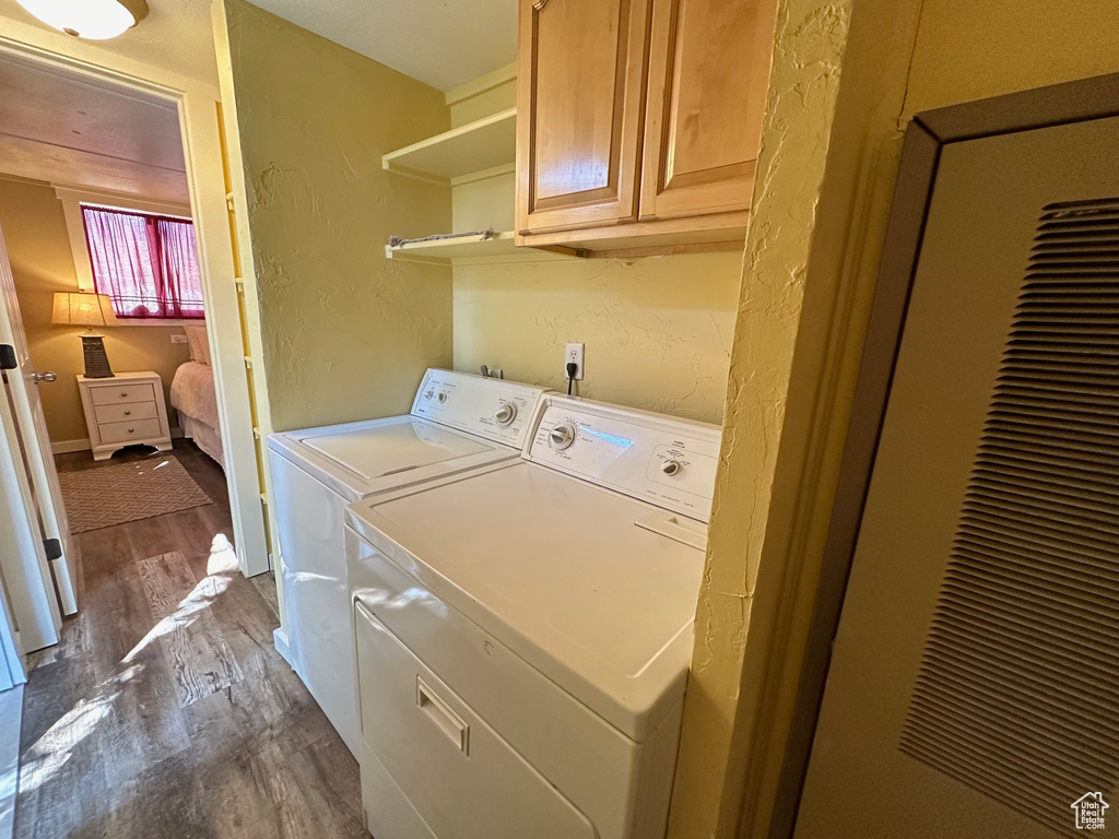 Laundry area featuring washer and dryer, hardwood / wood-style floors, and cabinets