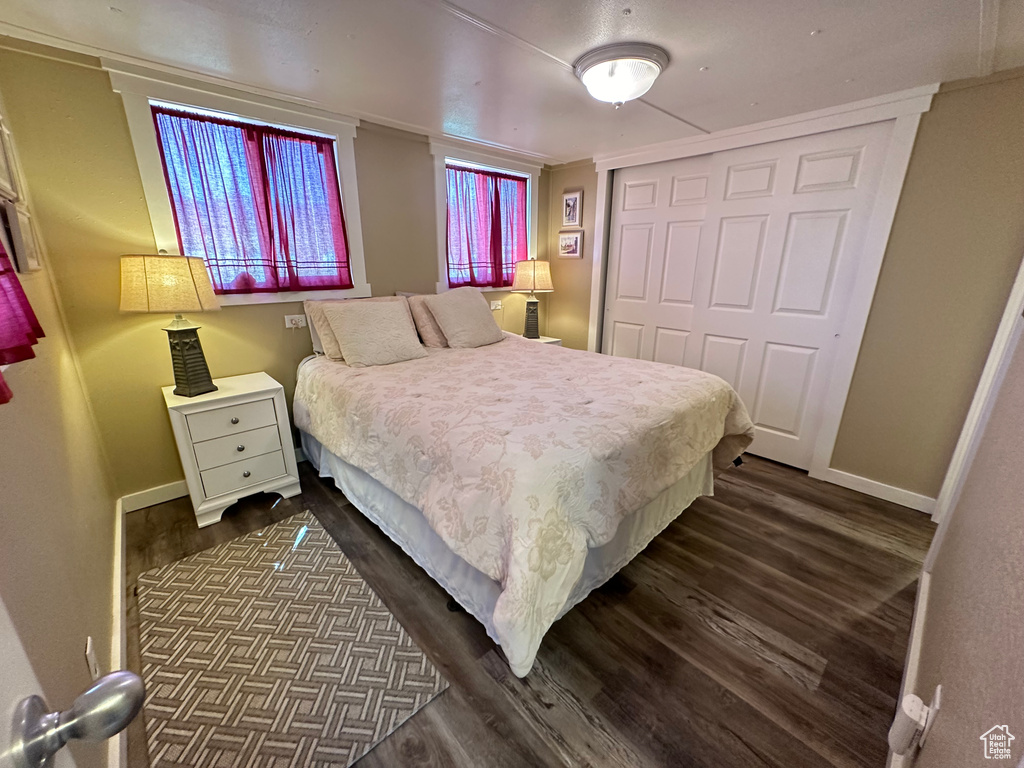 Bedroom with dark hardwood / wood-style floors, a closet, and ornamental molding