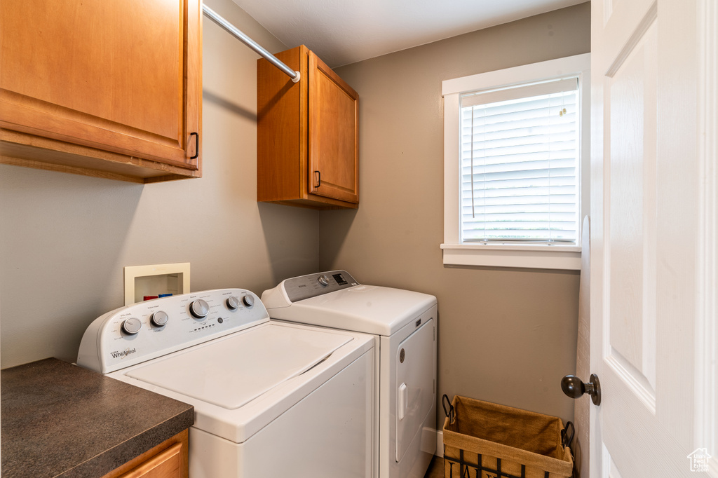 Clothes washing area featuring cabinets and independent washer and dryer