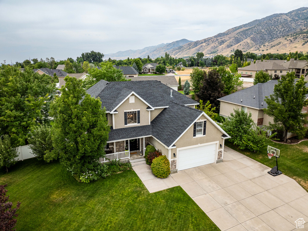 View of front of home featuring a mountain view, a porch, a garage, and a front lawn