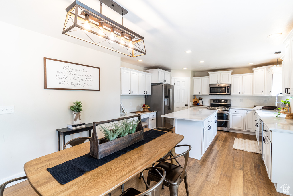 Kitchen featuring decorative light fixtures, white cabinetry, hardwood / wood-style flooring, and stainless steel appliances