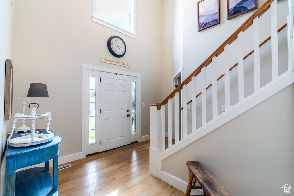 Entryway with light hardwood / wood-style floors and a towering ceiling