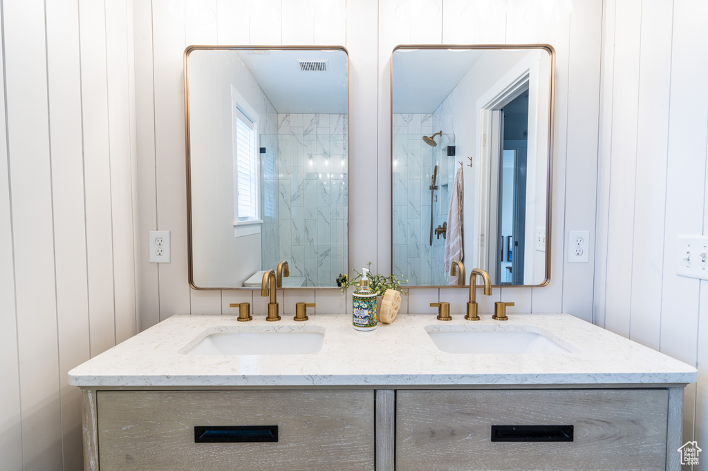 Bathroom with double vanity and tiled shower