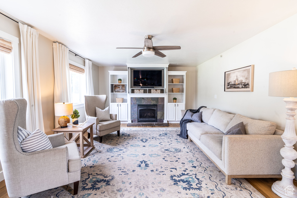 Living room featuring a tile fireplace, ceiling fan, and hardwood / wood-style flooring