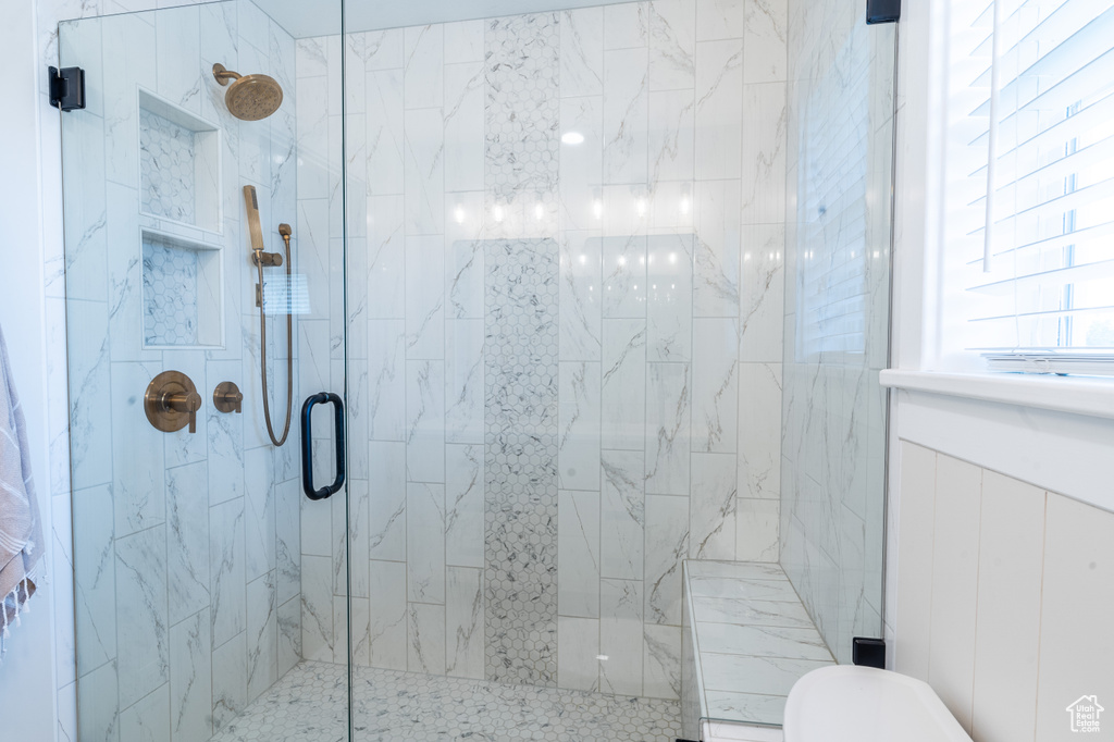 Bathroom featuring a shower with shower door and toilet