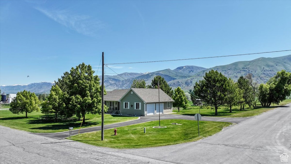 View of front of home with a garage, a mountain view, and a front yard