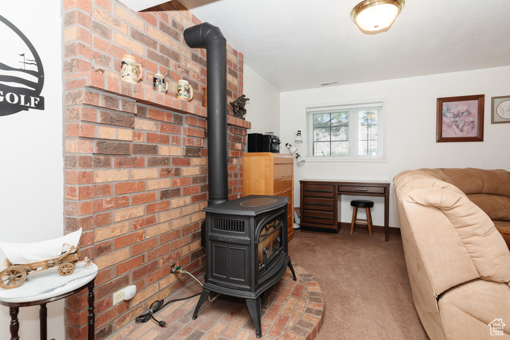 Living room with brick wall, carpet, and a wood stove