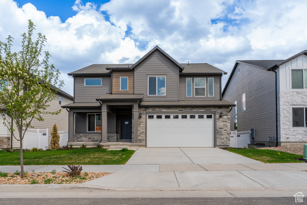 View of front facade with driveway, a garage, and stone siding