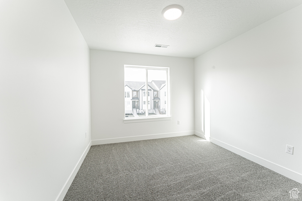 Carpeted spare room featuring a textured ceiling