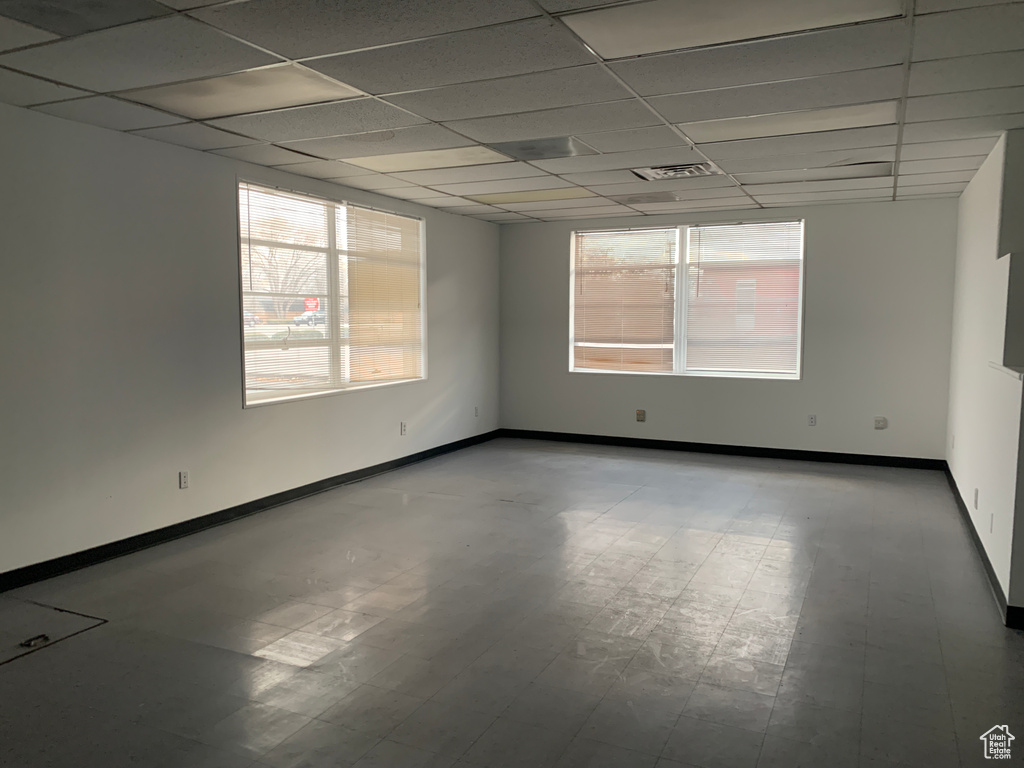 Unfurnished room featuring a paneled ceiling and a wealth of natural light