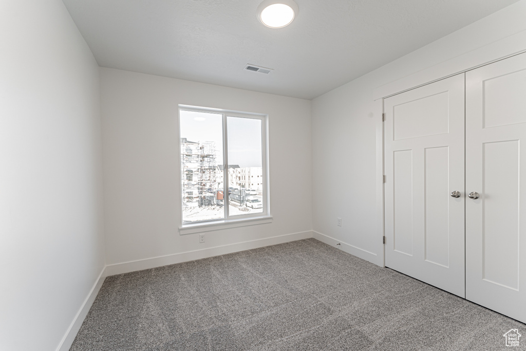 Unfurnished bedroom featuring light carpet and a closet