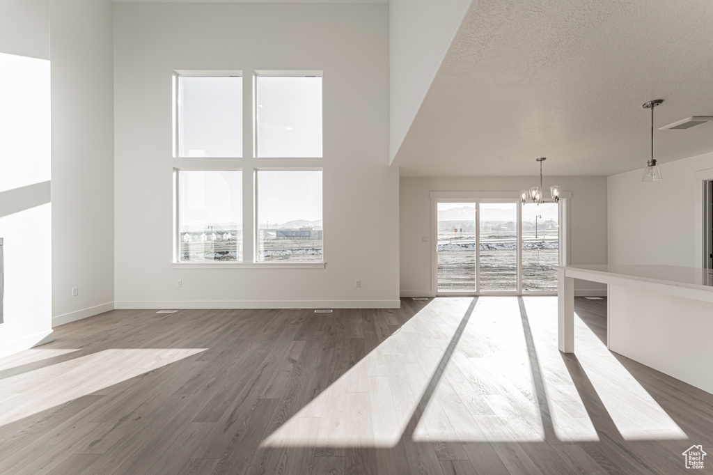 Unfurnished living room with hardwood / wood-style floors, a textured ceiling, and an inviting chandelier