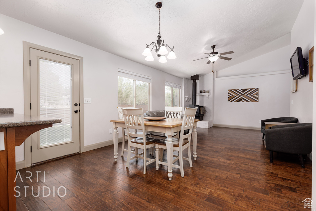 Dining area featuring ceiling fan with notable chandelier, dark hardwood / wood-style flooring, and vaulted ceiling