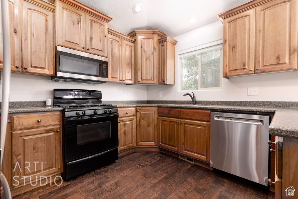 Kitchen with dark wood-type flooring, light brown cabinets, and stainless steel appliances