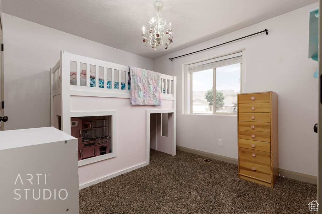 Unfurnished bedroom with a notable chandelier and dark carpet