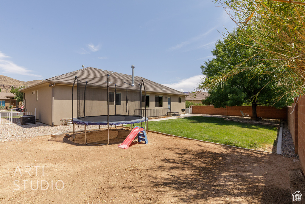 Back of house featuring a trampoline and a lawn