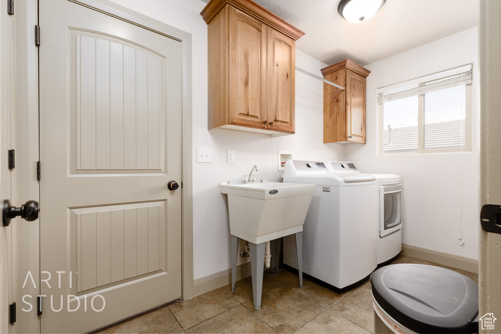 Laundry room with cabinets, washer and dryer, and light tile patterned floors