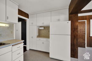 Kitchen with white fridge and white cabinets