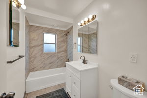 Full bathroom featuring tile patterned floors, vanity, tiled shower / bath combo, and toilet